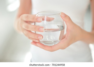 Female Hands Holding A Clear Glass Of Water. Slime Body On Background.