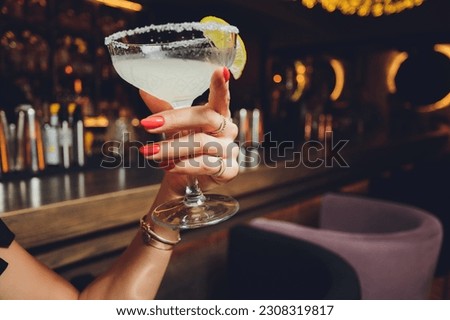 Female hands holding a clear glass of water. Slime body on background.