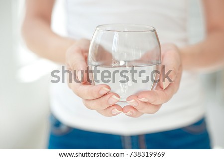 Female hands holding a clear glass of water. Slim body on background.