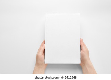 Female hands holding closed book with blank cover on light background
