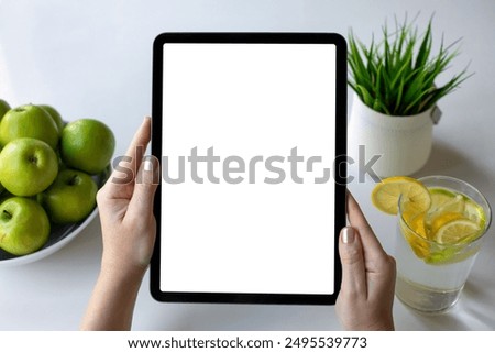 female hands holding computer tablet with isolated screen background of table with green apples in cafe