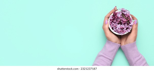 Female hands holding cup with lilac flowers on turquoise background with space for text, top view - Powered by Shutterstock