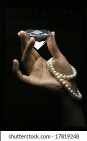 Female hands holding diamond with string of pearls