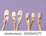 Female hands holding different slippers on lilac background