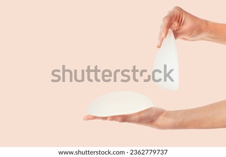Female hands holding different types of breast implants. Copy space. 