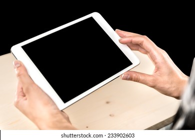 Female Hands Holding The Digital Tablet Similar To Ipad Mini With Isolated Screen On  Background Of A Wooden Table