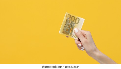 Female Hands Holding Euro Banknotes On A Yellow Background. Euro Money In Woman Hand. Euro Cash Background