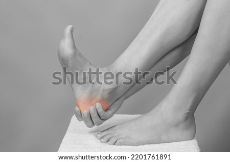 Female hands holding foot. Pain in  heel. Female feet on white towel. Heel massage.