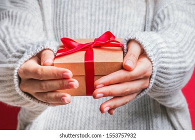 Female hands holding gift box with red ribbon close-up. Christmas, new year, birthday concept.