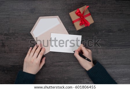 Female hands holding gift card and gift box over the black wooden table