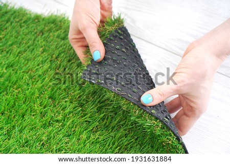 Female hands holding a green artificial turf roll
