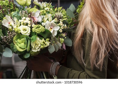 female hands holding green bouquet of Bronica, Brassica, Orchid, eustoma, hydrangea