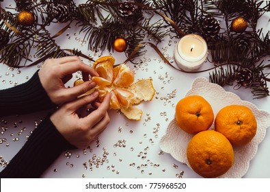 Female Hands Holding Mandarin Orange On Decorated Table. Winter Christmas Time. 