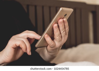 Female hands holding mobile phone lying bed at home close up doing purchases applications. Middle-aged  mature woman using texting reading message smartphone sitting sofa social networks - Powered by Shutterstock