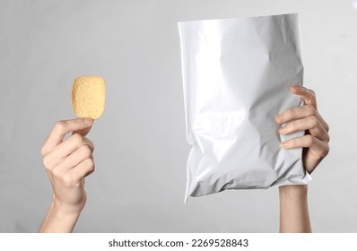 Female hands holding mock up pack of chips on gray background. Template for design