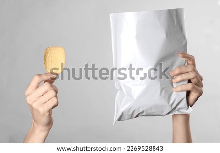 Female hands holding mock up pack of chips on gray background. Template for design