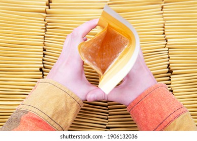 Female Hands Holding A Padded Envelope Open Over A Box Full Of Yellow Mailers