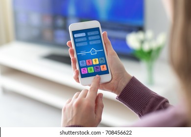 Female Hands Holding Phone With App Smart Home Screen In Room House