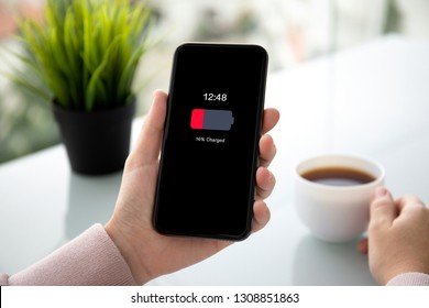 Female Hands Holding Phone With Low Charged Battery On Screen In A Summer Cafe