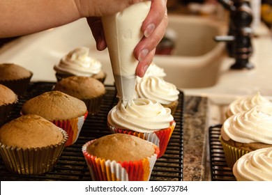 Female Hands Holding Piping Bag Filled With Cream Cheese Frosting Decorating Cupcakes