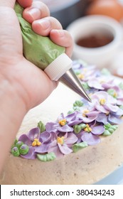 Female Hands Holding Piping Bag Filled With Buttercream Frosting Decorating Cake