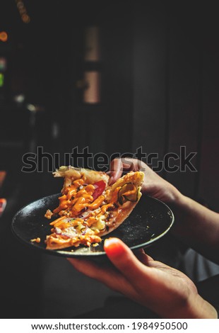 female hands holding a plate with a slice of pizza in a cafe