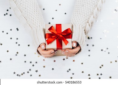 Female hands holding present with red bow on white rustic sparkling background. Festive backdrop for holidays: Birthday, Valentines day, Christmas, New Year. Flat lay - Shutterstock ID 540186553
