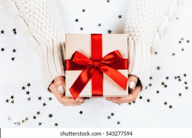 Female hands holding present with red bow on white rustic sparkling background. Festive backdrop for holidays: Birthday, Valentines day, Christmas, New Year. Flat lay style - Shutterstock ID 543277594