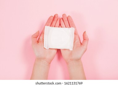 Female Hands Holding A Sanitary Pad On A Pink Background