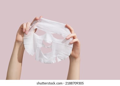 Female hands holding sheet of white mask on pink background. High quality photo - Shutterstock ID 2188709305