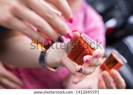 Female hands holding shots of alcohol at the festival