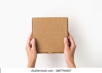 female hands holding a small cardboard box on a white background. packaging and delivery concept, top view