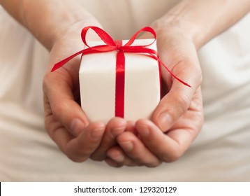 Weibliche Hände, die kleine Geschenk mit Band.