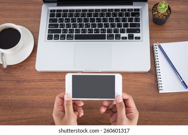 female hands holding smartphone on the table in the office - Shutterstock ID 260601317