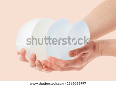  Female hands holding stack of different types of breast implants.