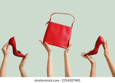 Female hands holding stylish bag and high heels on pale green background - Powered by Shutterstock