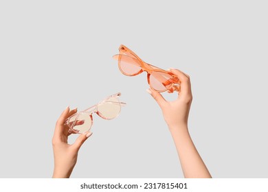 Female hands holding stylish sunglasses on white background