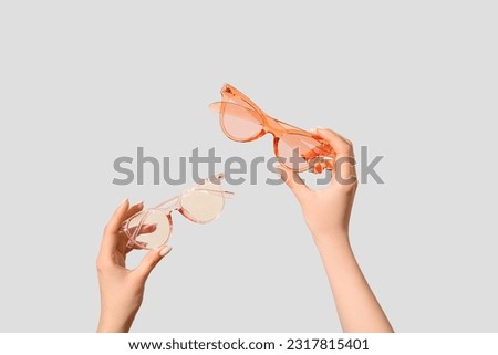 Female hands holding stylish sunglasses on white background