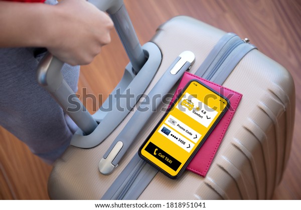 female hands holding suitcase and phone
with application call taxi on screen at
airport