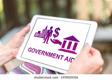 Female Hands Holding A Tablet With Government Aid Concept