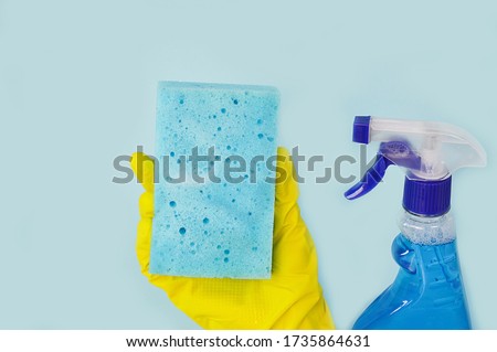 Female hands are holding tools for washing, cleaning, window cleaning products: squeegee, sponge, window cleaning liquid, gloves on a blue background. Cleaning service. copy space.