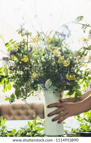 Female hands holding flower vase with wild flowers