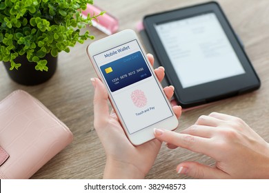 Female Hands Holding White Phone With App Mobile Wallet On The Screen On The Women Table