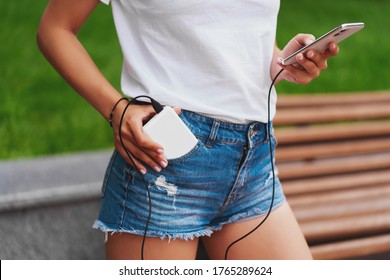 Female Hands Are Holding  White Powerbank Charger And White Phone. Still Life Modern Digital Concept.