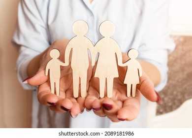 Female hands are holding a wooden figurine of a family. Selective focus. - Shutterstock ID 2089181986