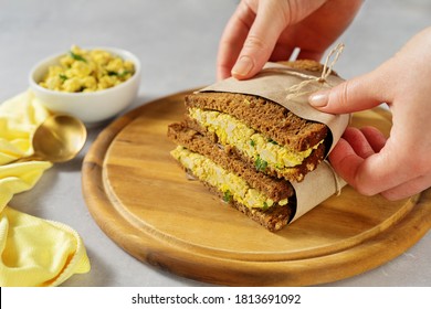 Female Hands Holding Wrapped In Paper Sandwiches With Vegan Egg Salad Made From Tofu