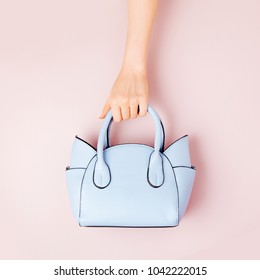 Female hands holds handbag on pink  background . Flat lay, top view. Spring fashion concept in pastel colored - Shutterstock ID 1042222015