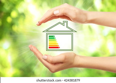 Female hands and house with energy efficiency scale image on natural background - Shutterstock ID 424381879