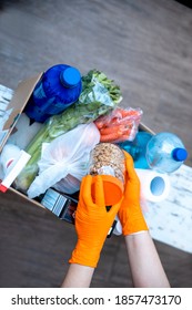 Female Hands In Hygenic Gloves  Packing Humanitarian Aid In Donation Box. Volunteer Loading Food In Charitable Foundation. Helping In Crises And Homeless 