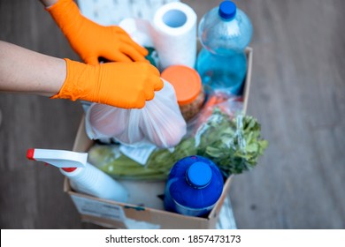 Female Hands In Hygenic Gloves  Packing Humanitarian Aid In Donation Box. Volunteer Loading Food In Charitable Foundation. Helping In Crises And Homeless 